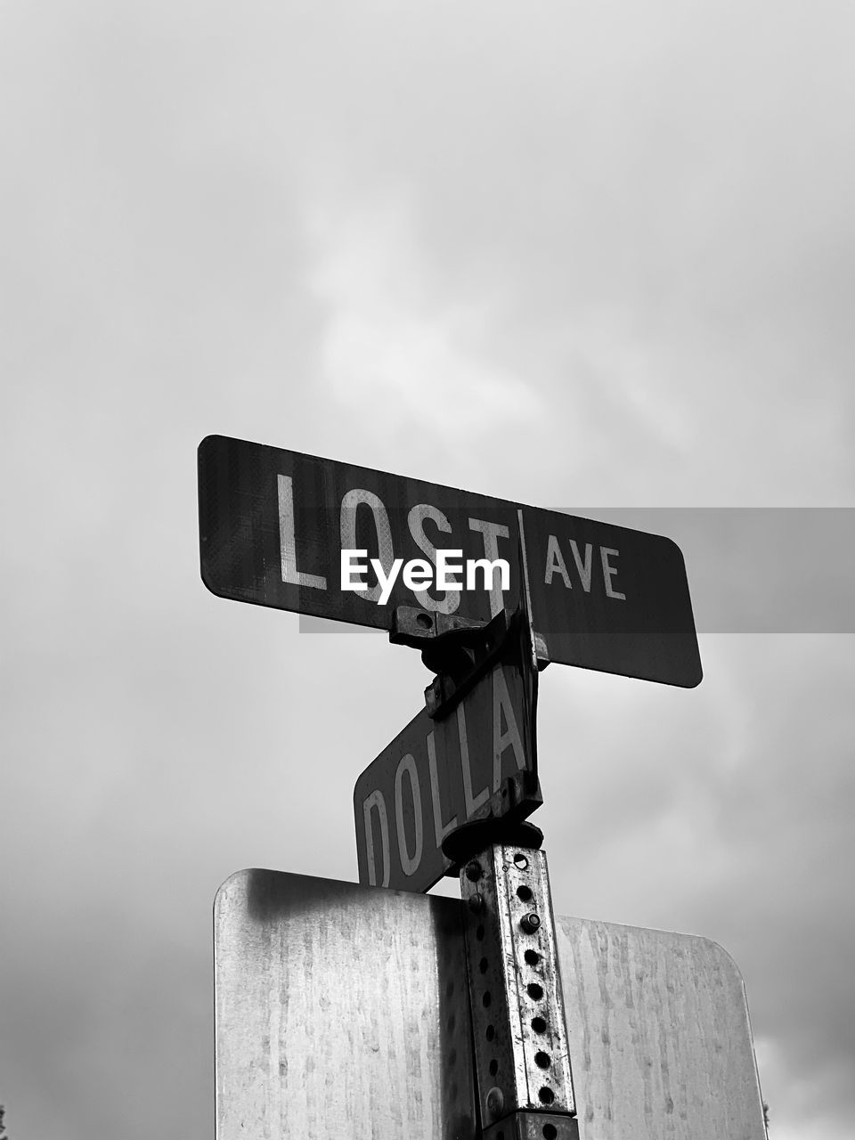 Low angle view of road sign against sky that says lost