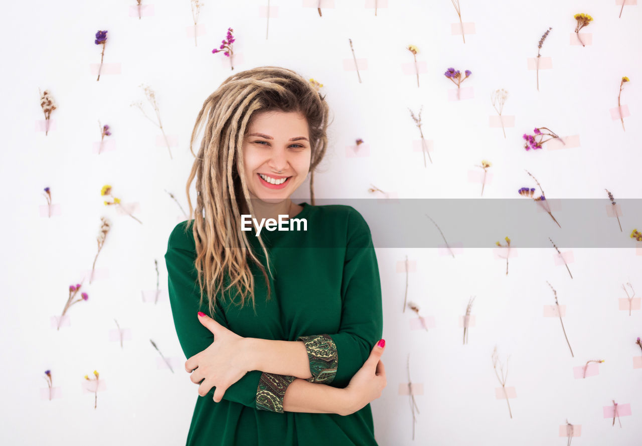 Portrait of smiling young woman standing against wall