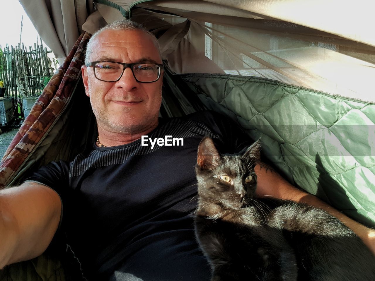 Portrait of man sitting with cat in tent 