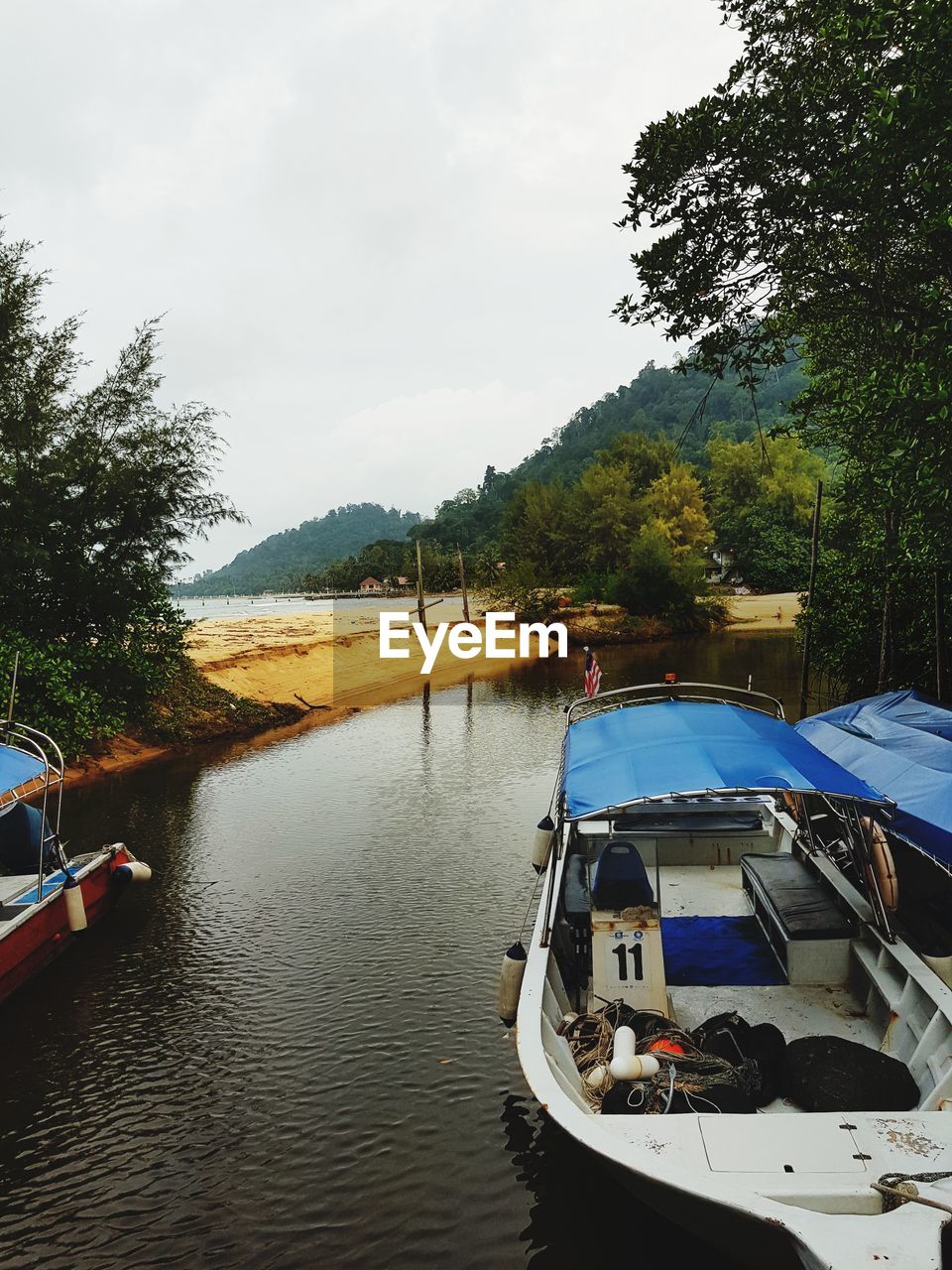 BOATS MOORED AT LAKE AGAINST SKY