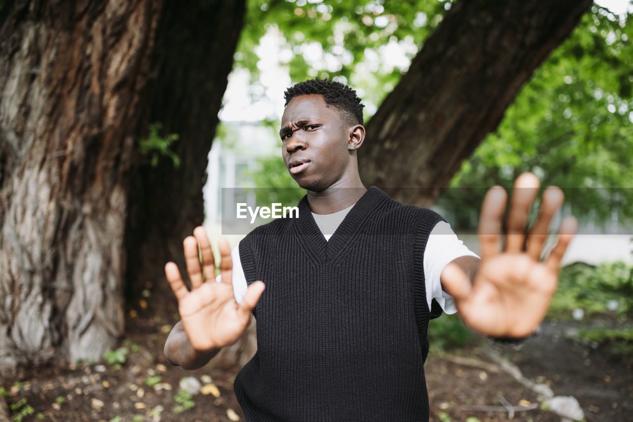 Shocked young 20s african man doing no stop sign with palms of hands