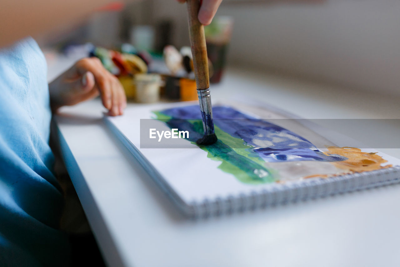 Midsection of boy painting at home