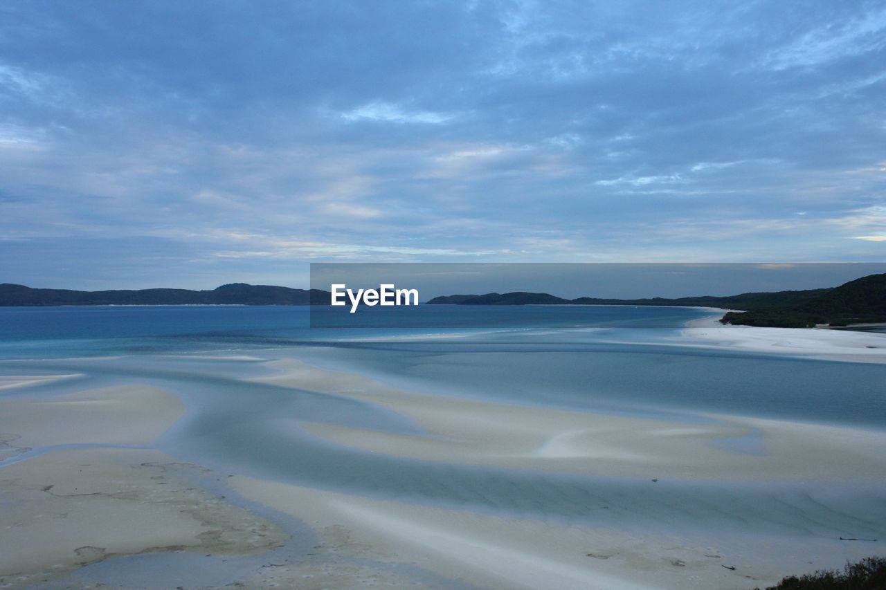 Idyllic view of beach against cloudy sky