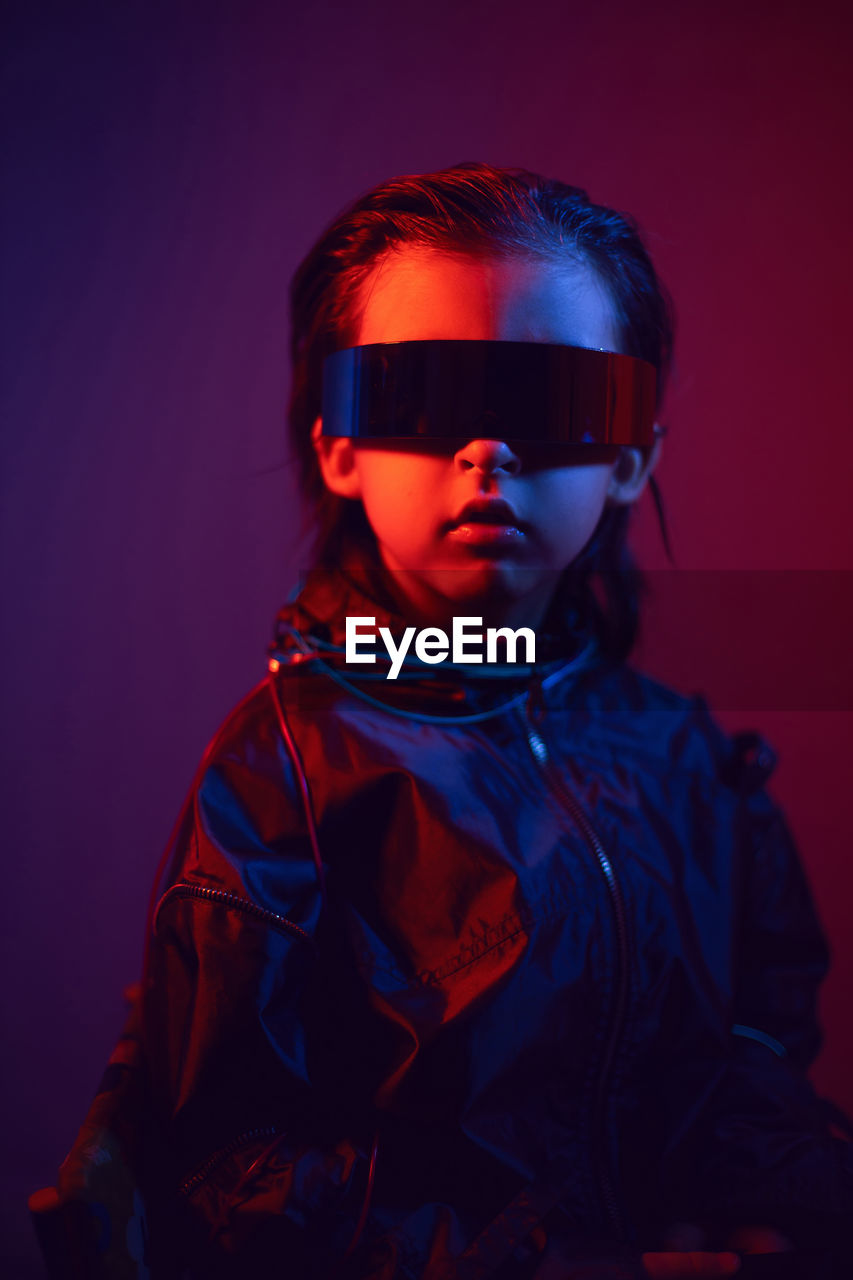 Portrait cyberpunk boy child in vr glasses in blue and red tones. game, virtual reality