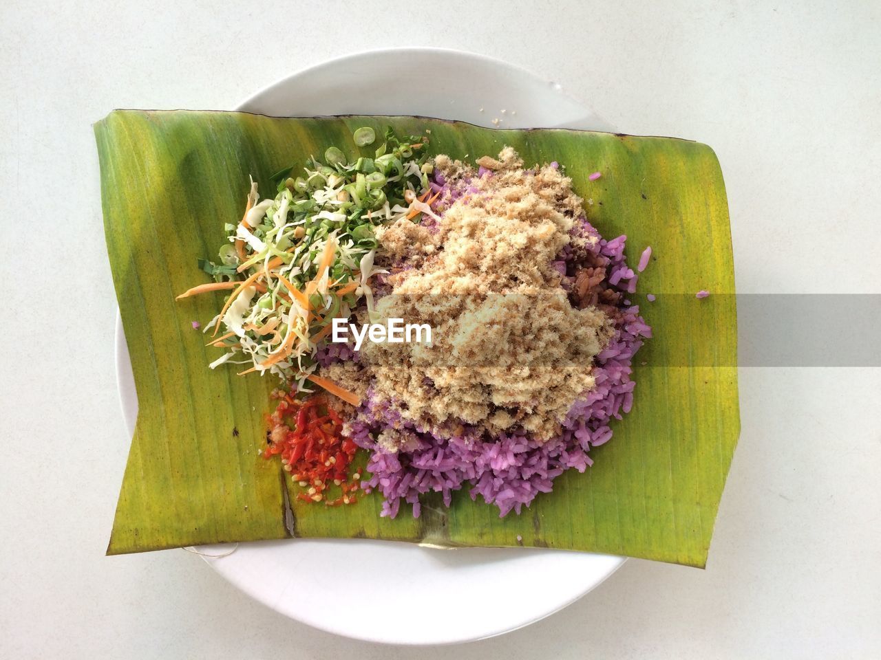 Directly above view of food served on banana leaf in plate over white background