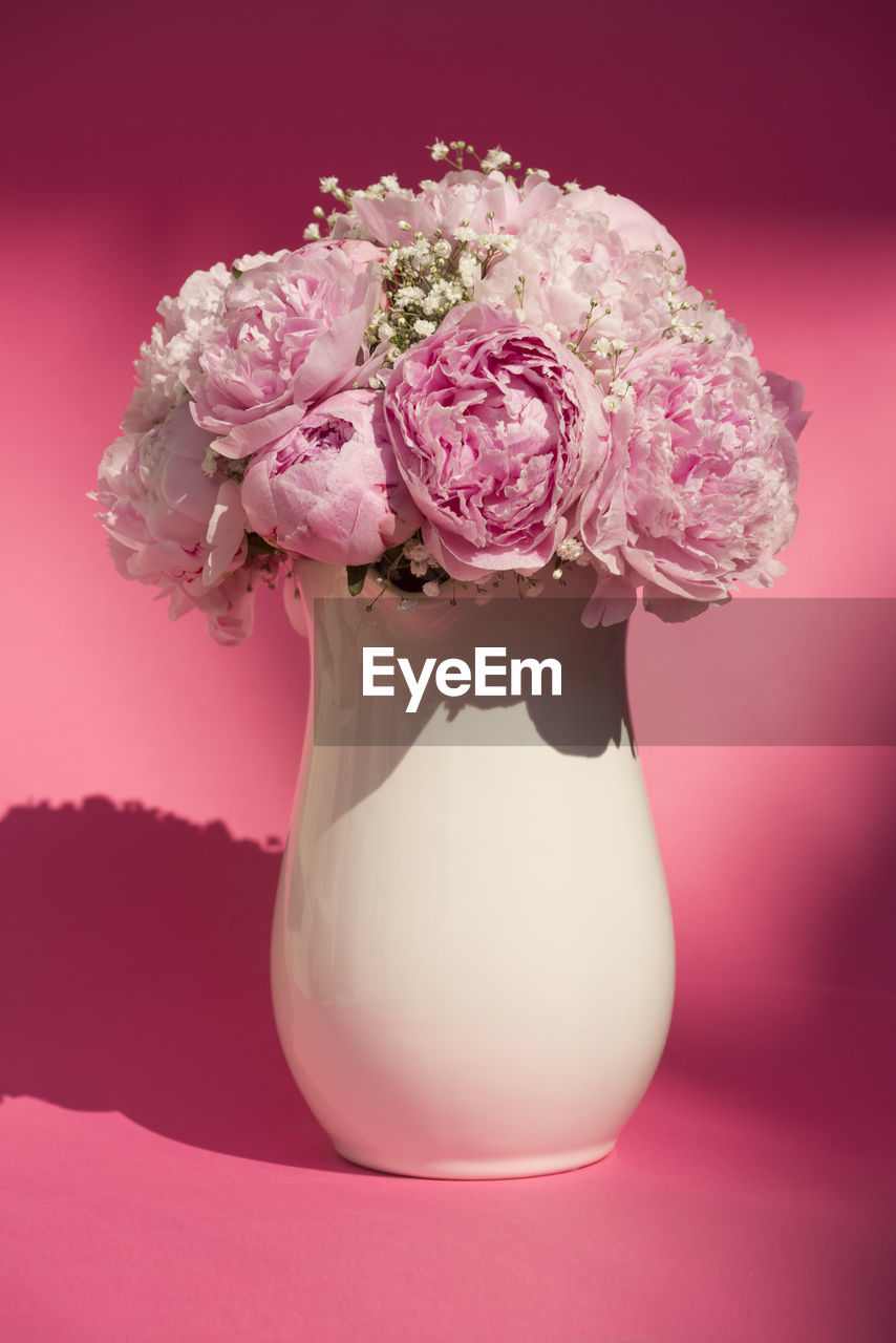 Beautiful wedding bouquet in a white vase, on a pink background in summertime.