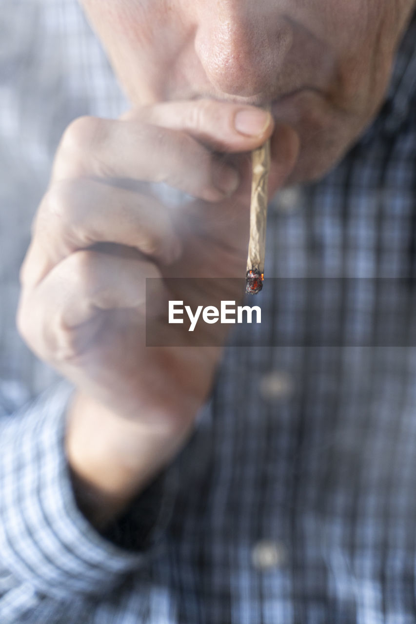 Senior man at home smoking marihuana joint