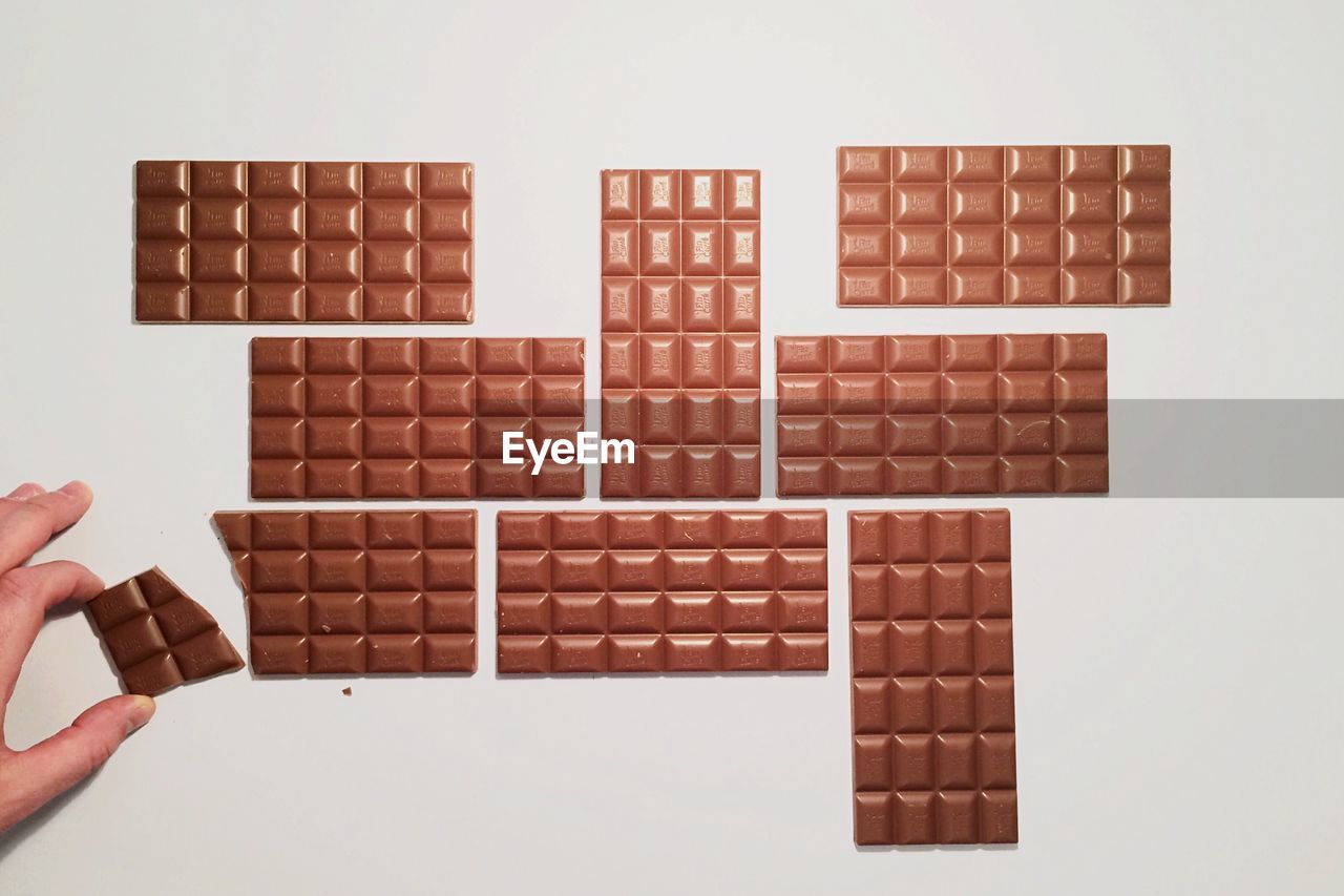 Hand arranging chocolate bars on white background