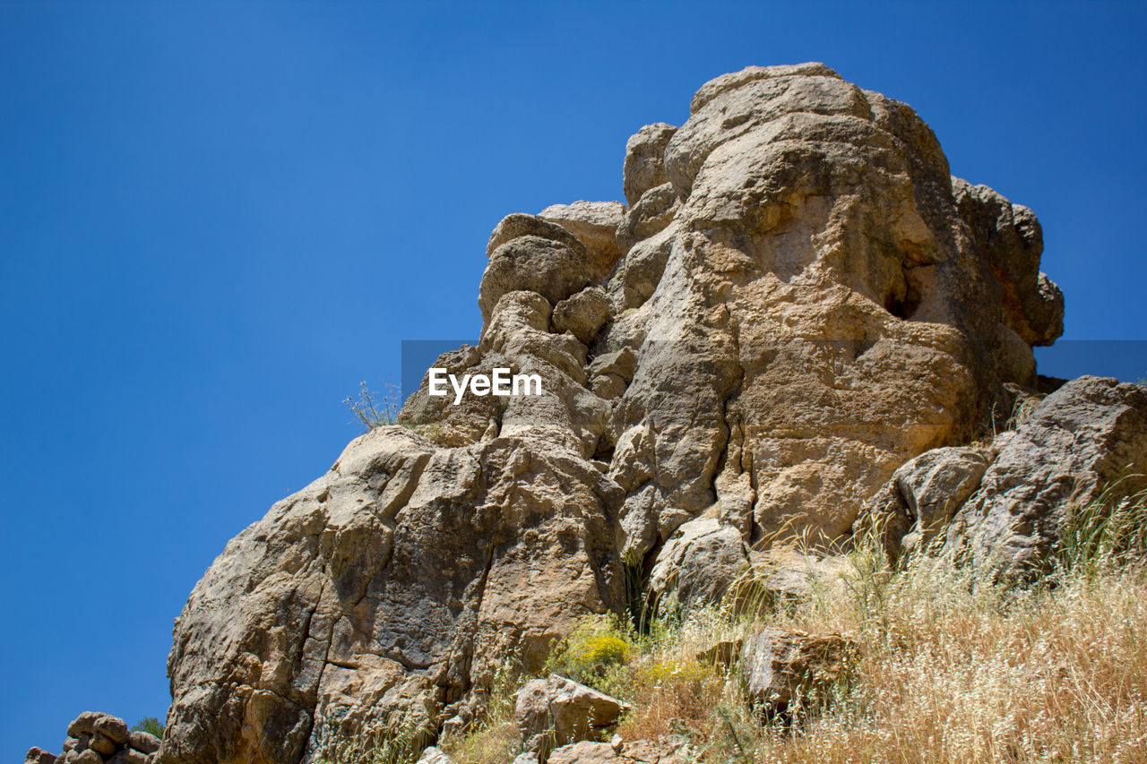 LOW ANGLE VIEW OF ROCK FORMATION AGAINST CLEAR SKY