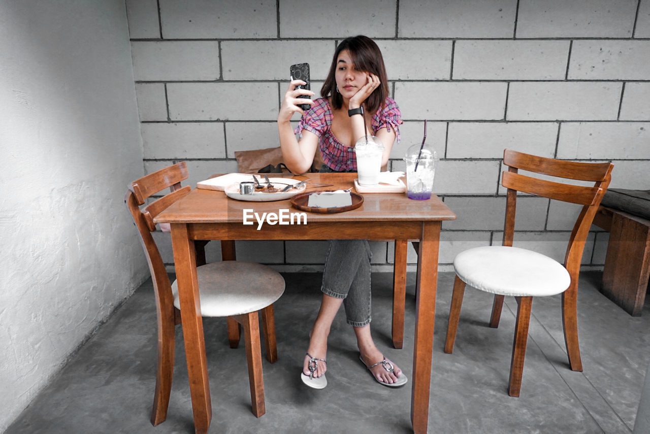 FULL LENGTH OF WOMAN SITTING ON TABLE