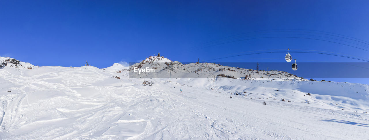 snow, winter, cold temperature, mountain, piste, scenics - nature, environment, landscape, sky, nature, beauty in nature, blue, mountain range, winter sports, ski mountaineering, skiing, ski equipment, clear sky, ski touring, resort, day, white, ski, sports, travel, travel destinations, land, non-urban scene, tranquil scene, tranquility, holiday, vacation, snowcapped mountain, sunny, outdoors, trip, sunlight, sports equipment, copy space, adventure