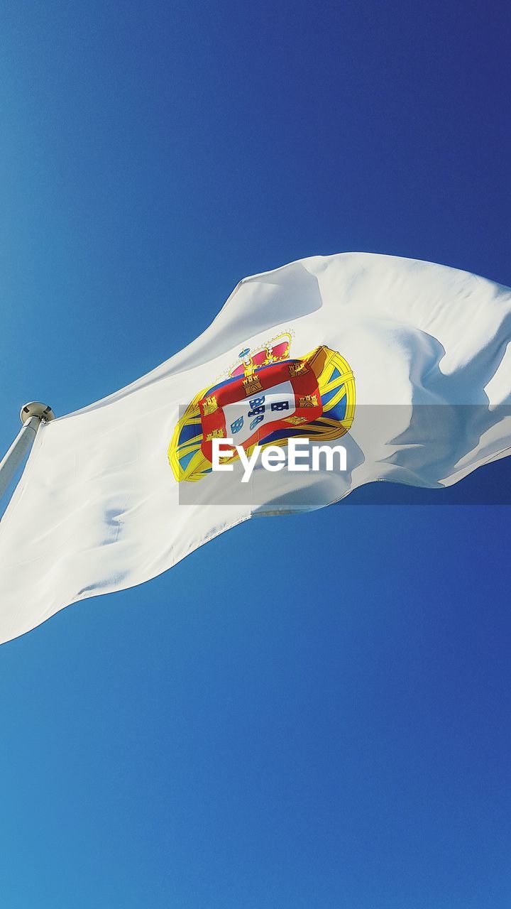 Low angle view of flag against clear blue sky