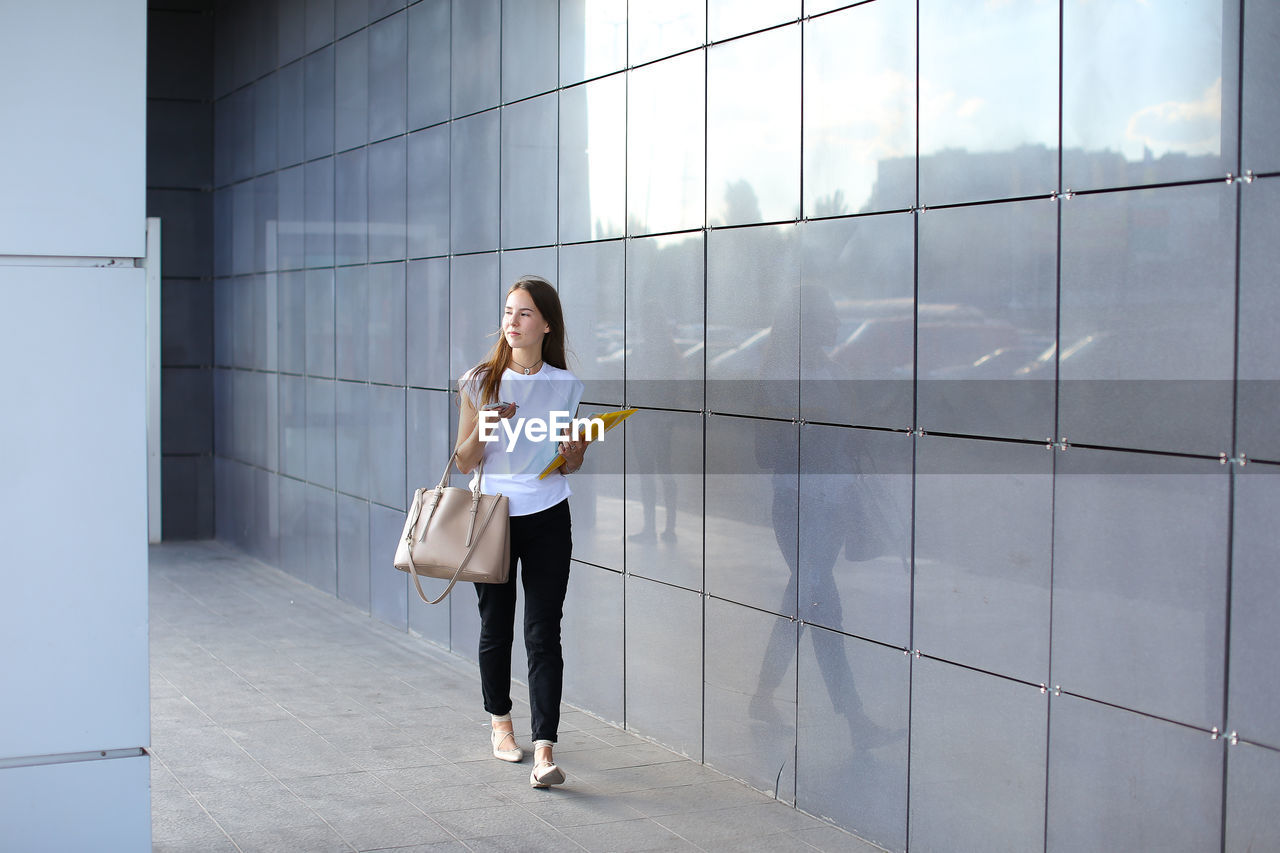 Full length of woman standing against building