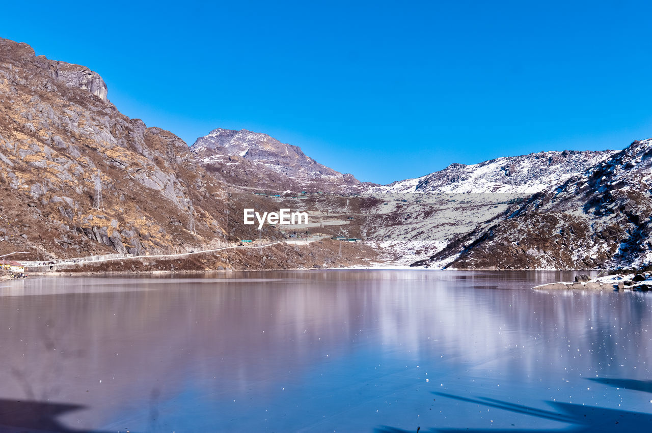 SCENIC VIEW OF LAKE BY SNOWCAPPED MOUNTAINS AGAINST BLUE SKY