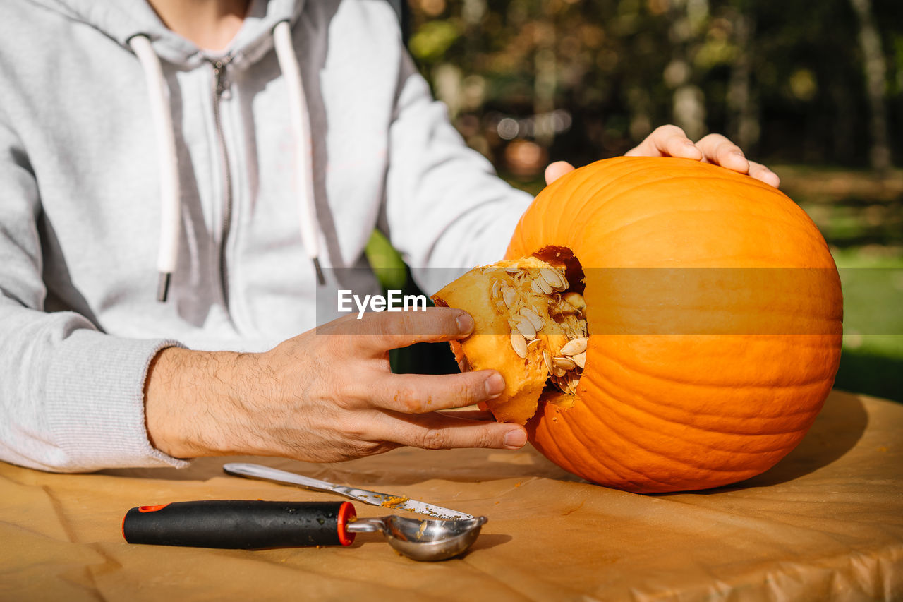 Midsection of man holding pumpkin