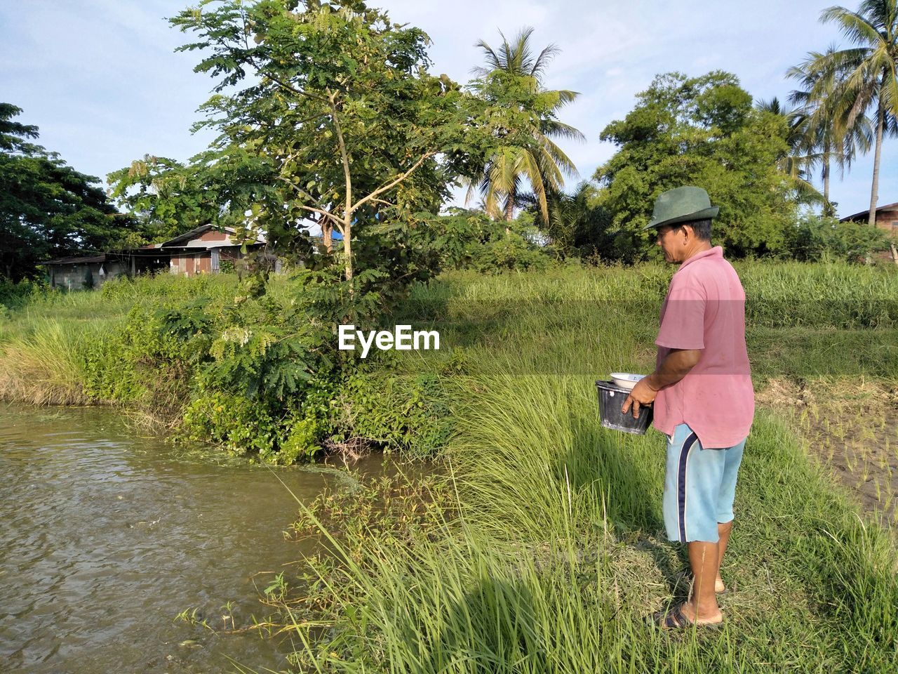 Man holding containers while standing by lake