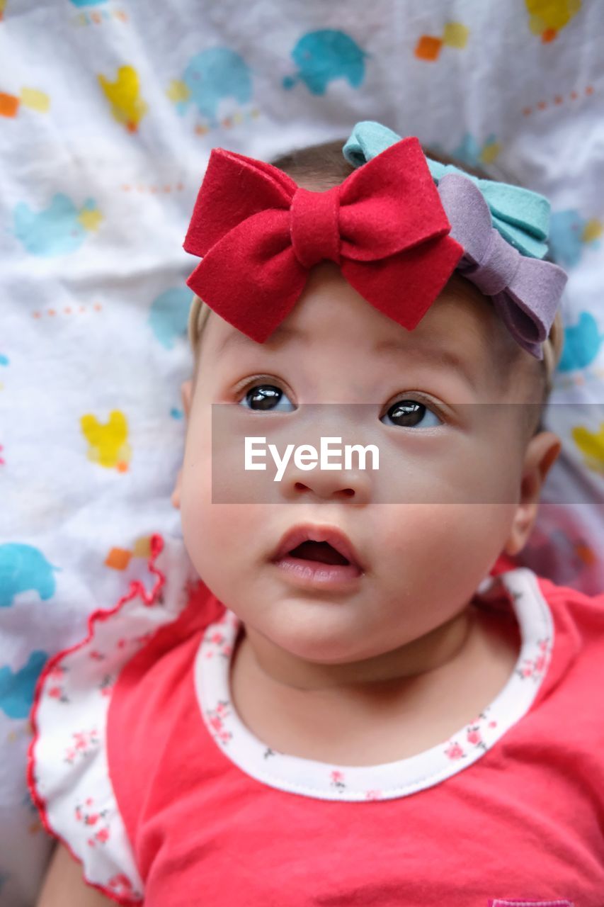 High angle view of cute baby girl looking away while lying on bed at home