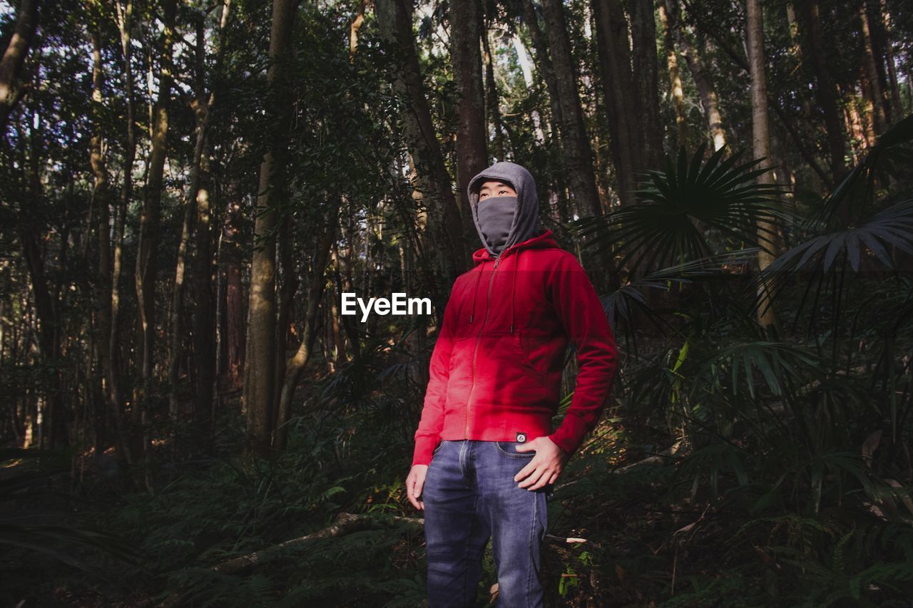 Man with covered face looking away in forest