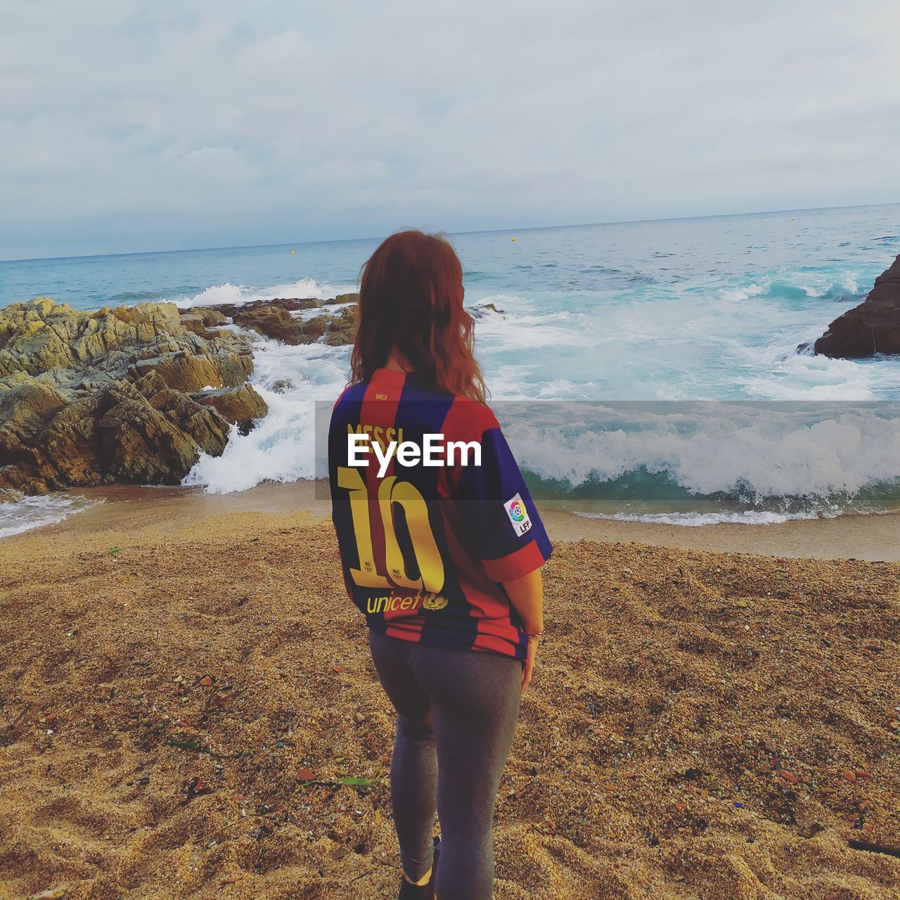 REAR VIEW OF WOMAN LOOKING AT BEACH AGAINST SKY