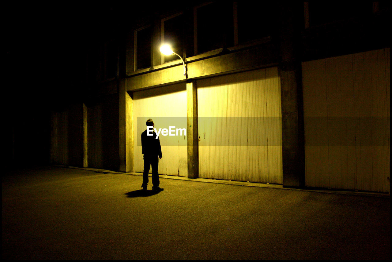 Full length of man standing by illuminated building at night