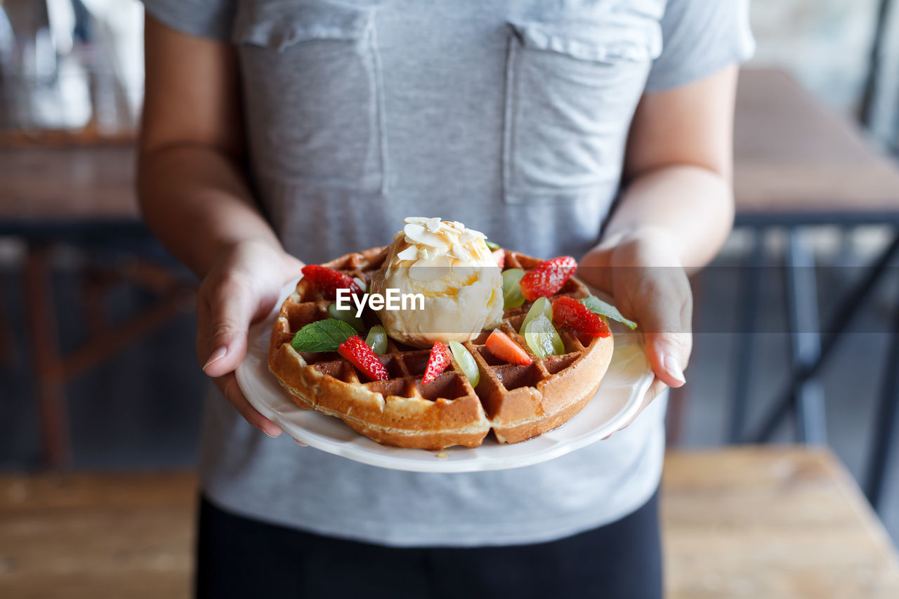 Midsection of woman holding waffle