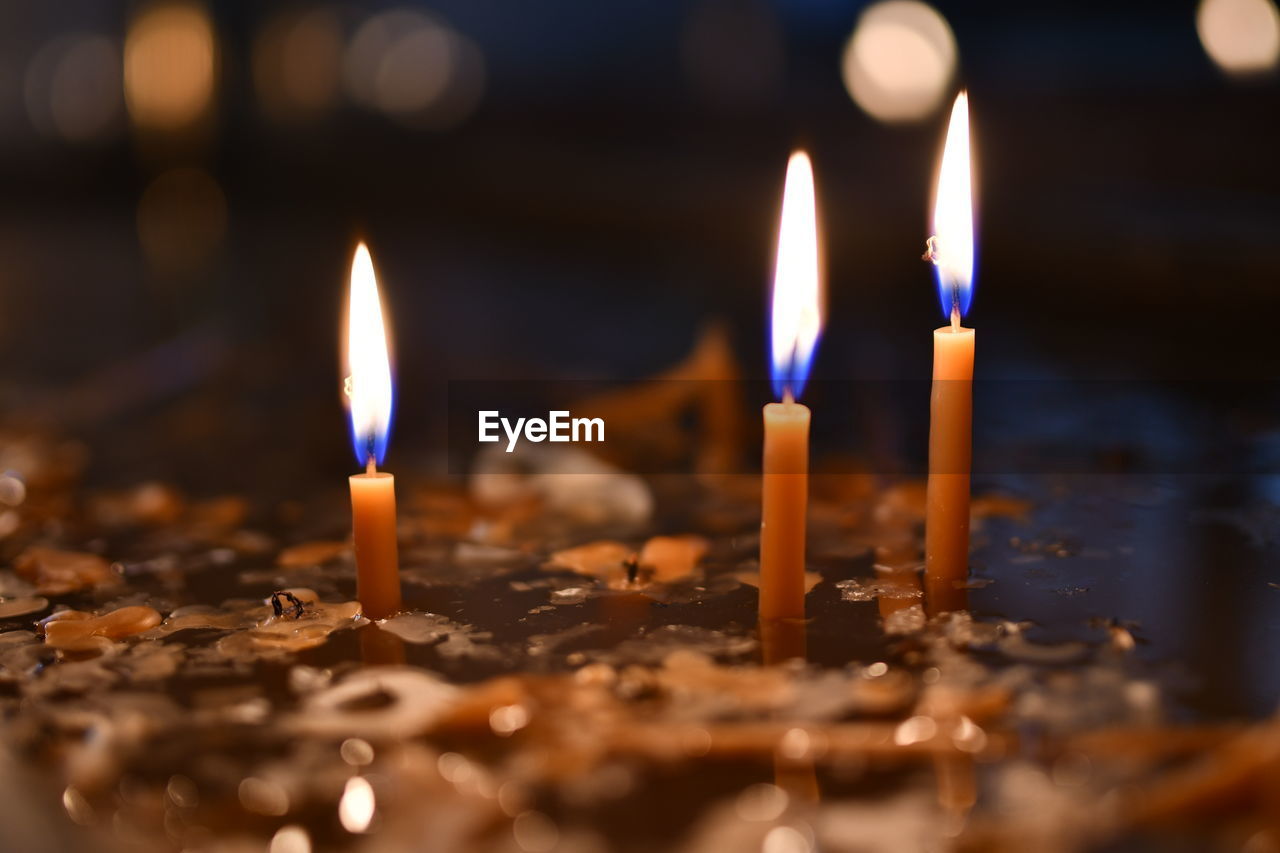 CLOSE-UP OF LIT CANDLES IN TEMPLE