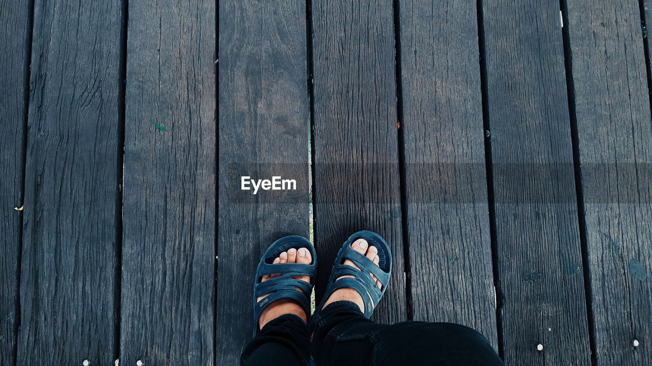 Low section of man standing on wooden floor