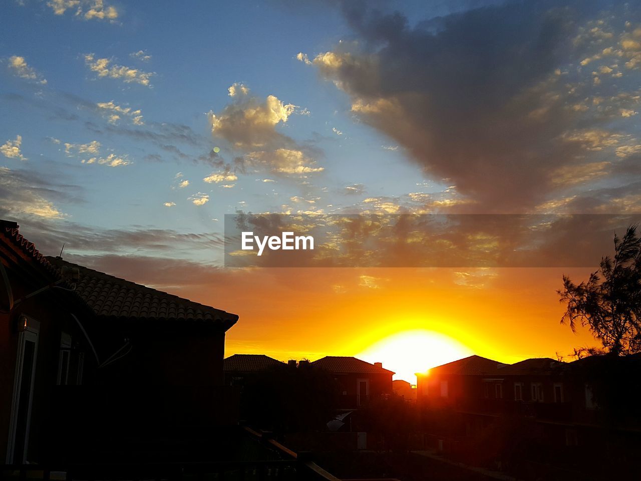 SILHOUETTE HOUSES AGAINST ORANGE SKY