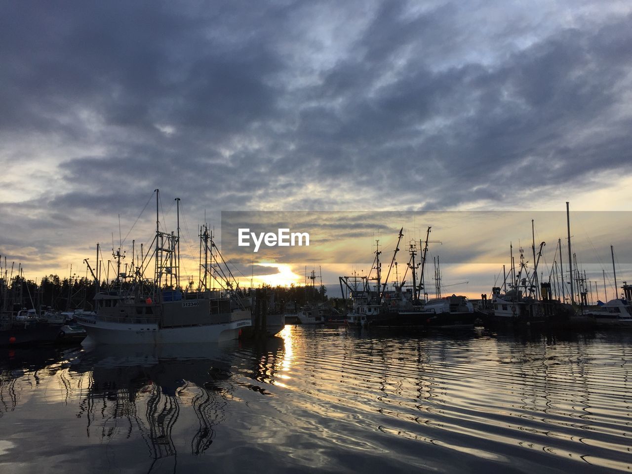 Sailboats in sea at sunset