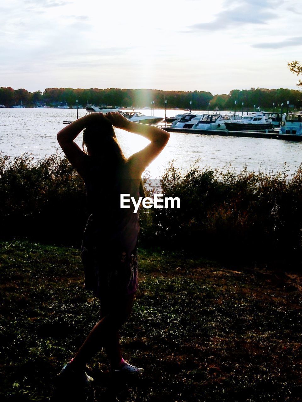 REAR VIEW OF WOMAN LOOKING AT LAKE AGAINST SKY