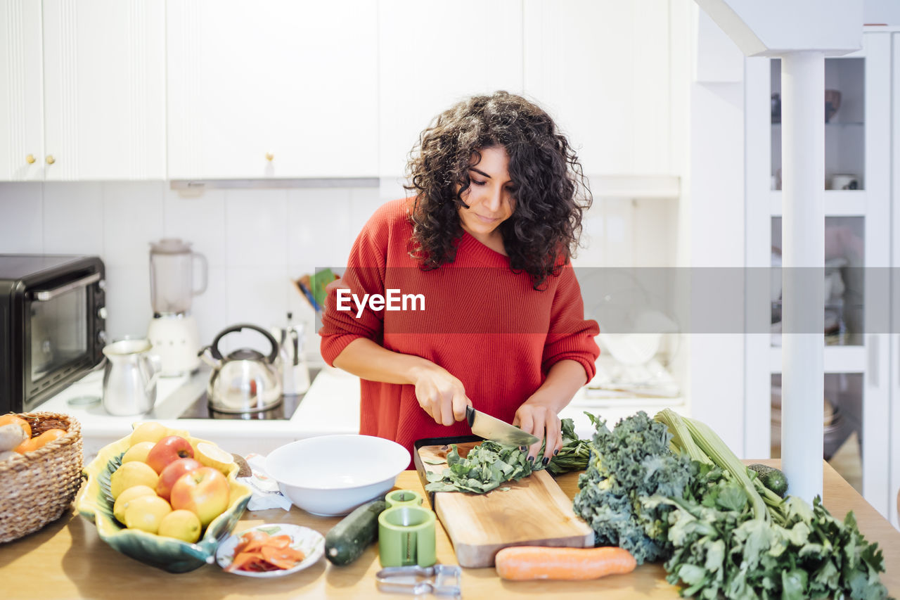 Brunette woman making a healthy green salad.