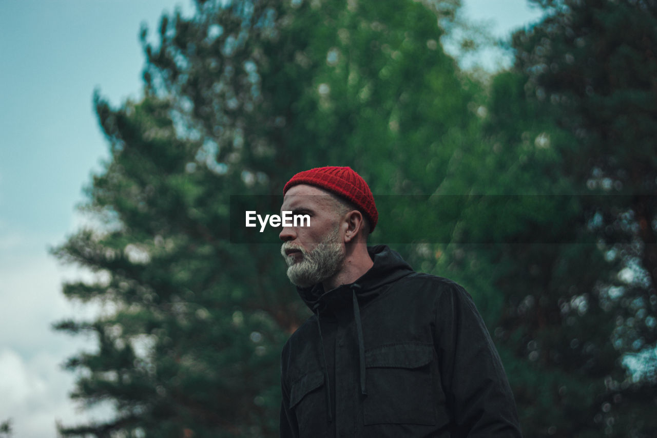 Portrait of man looking away against trees during winter