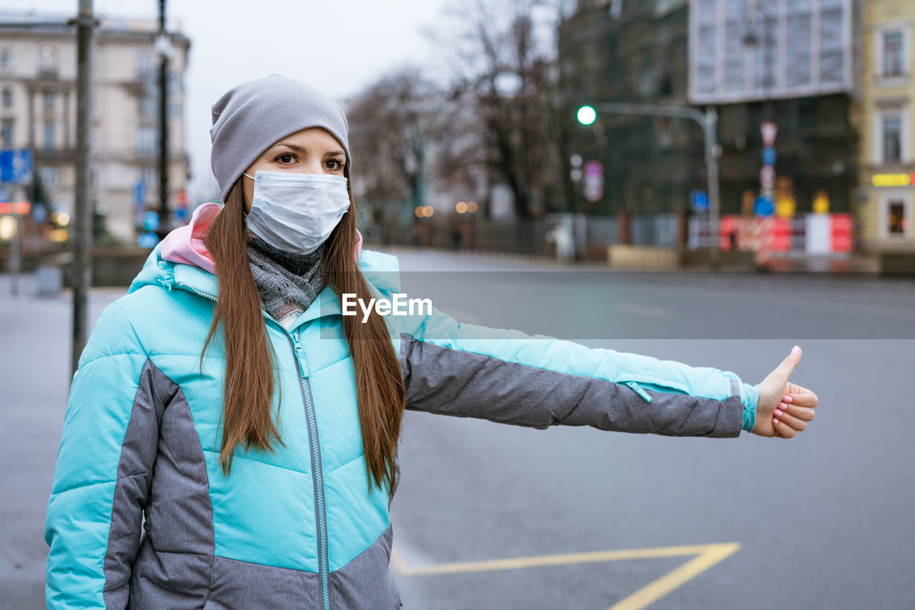 Woman wearing mask gesturing while standing on road