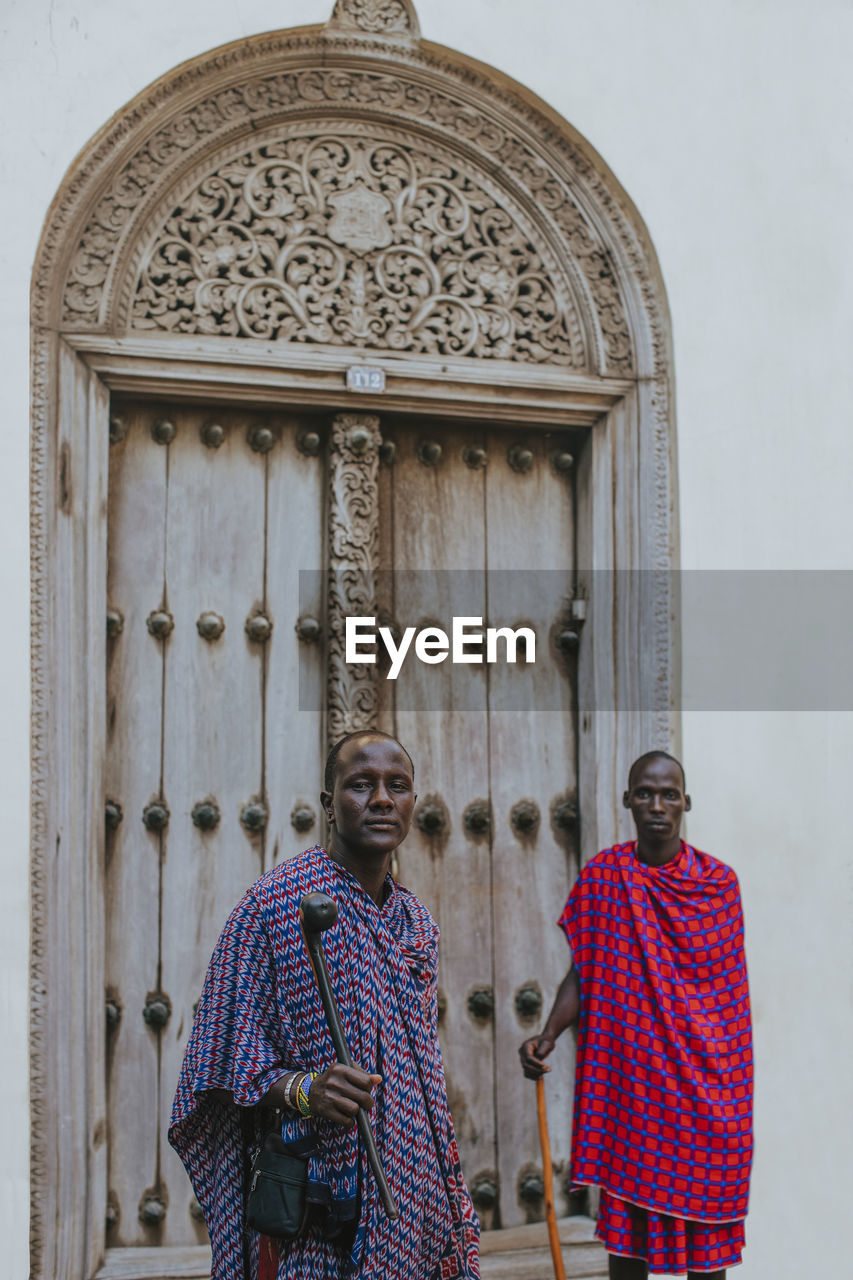 Two masai men standing in front of a traditional door in old town