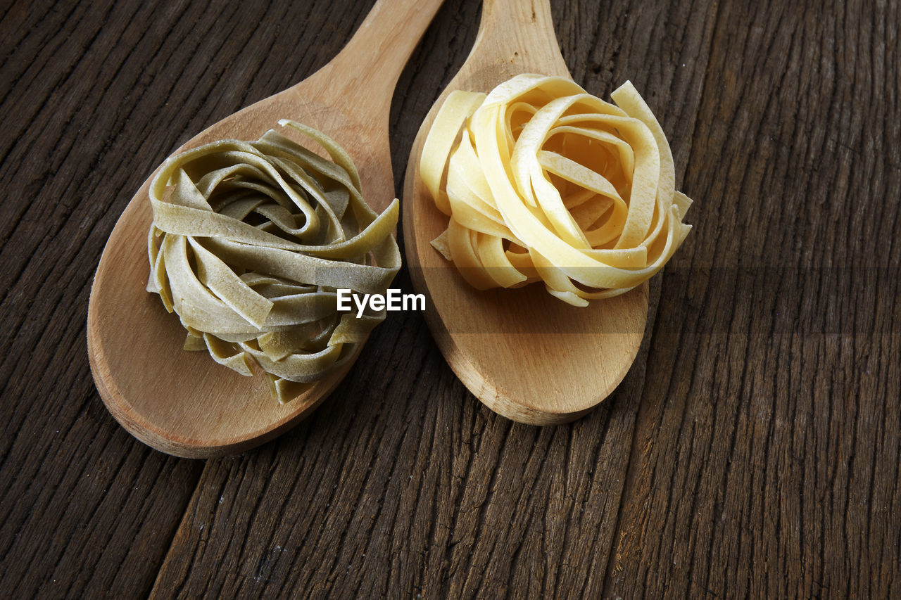 Close-up of tagliatelle pasta in wooden spoons on table