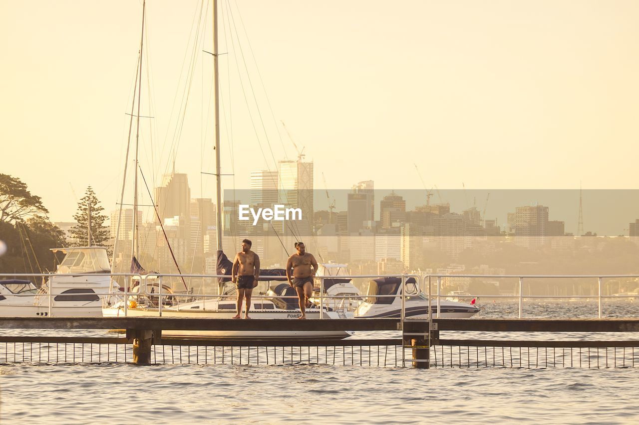 PEOPLE ON SAILBOAT IN RIVER AGAINST SKY