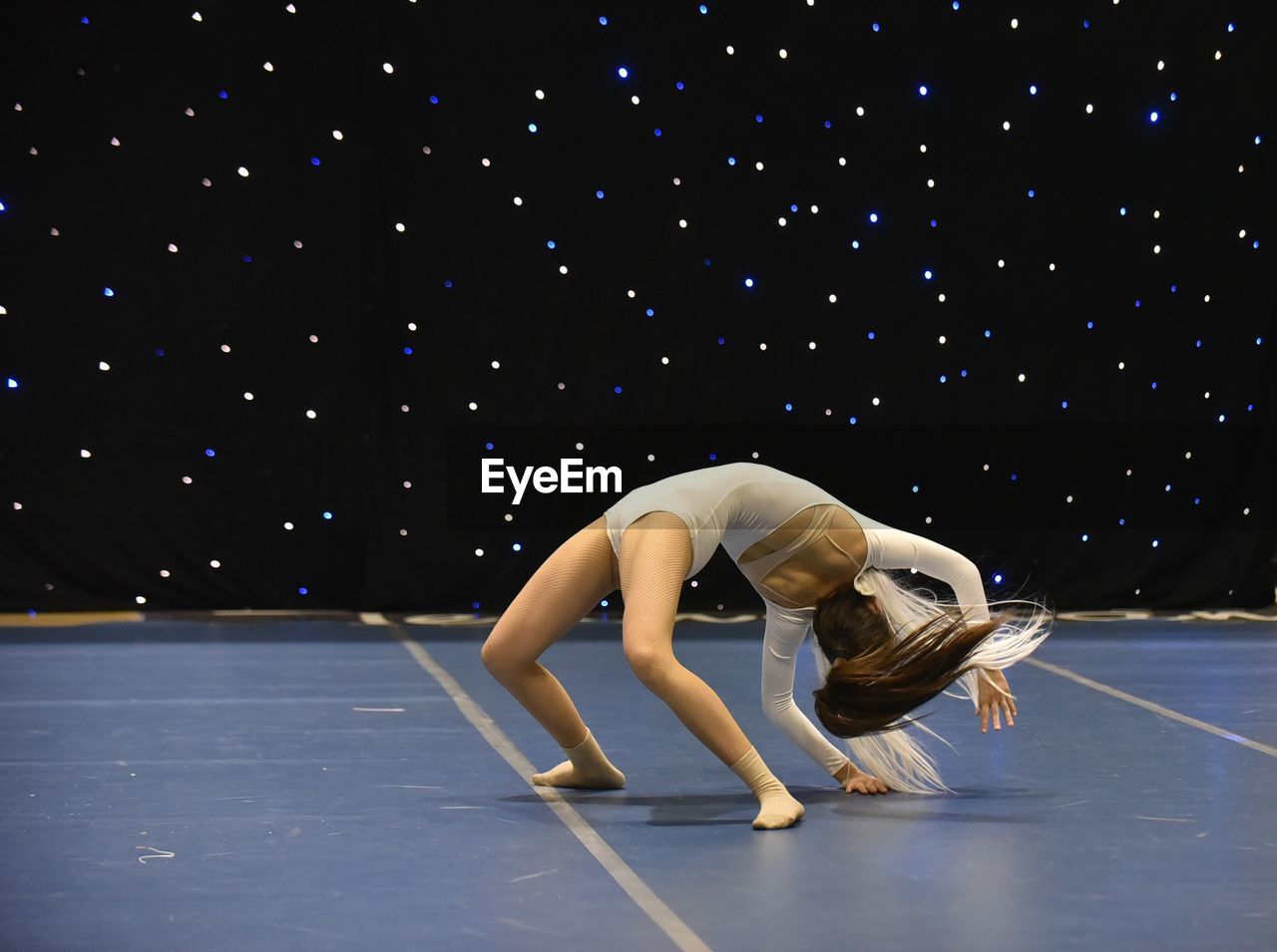 Young teenage girl in white jersey perform modern dance on stage