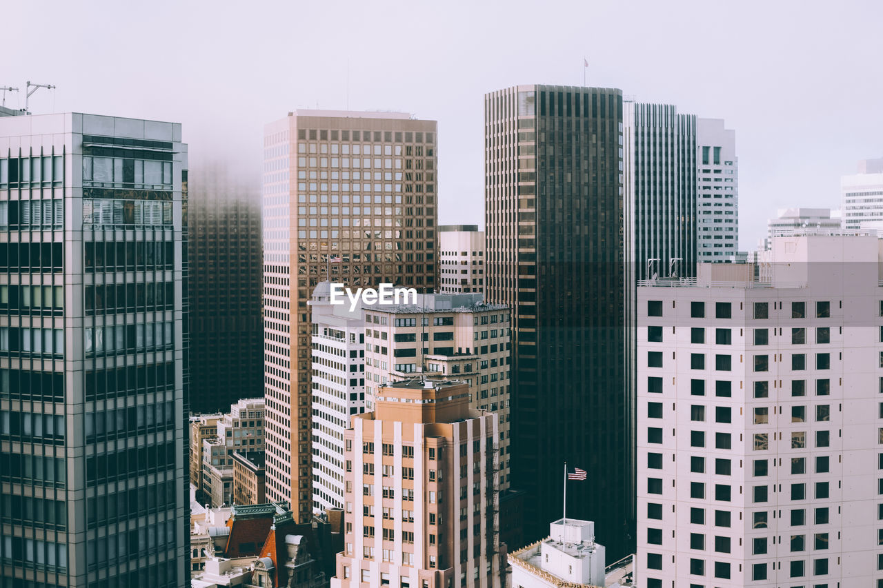 Buildings in city against foggy sky