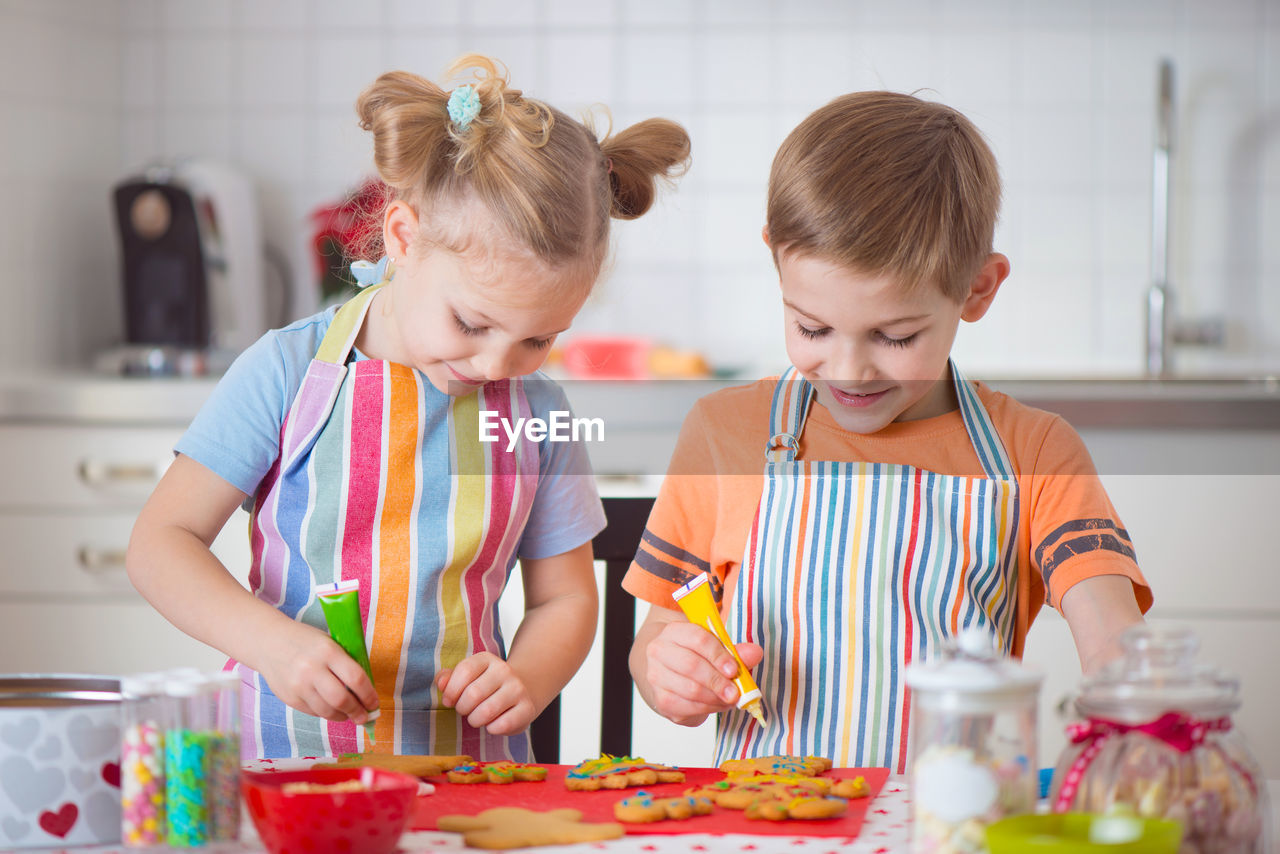 View of cute girl and boy preparing food at kitchen