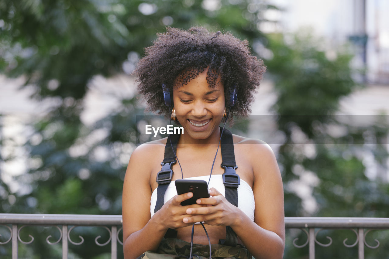 Smiling woman listening music while sitting outdoors