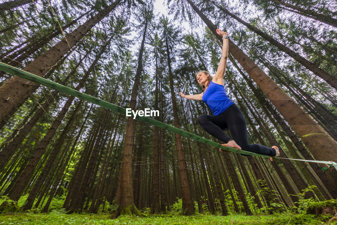 Young woman balancing on slackline in forest