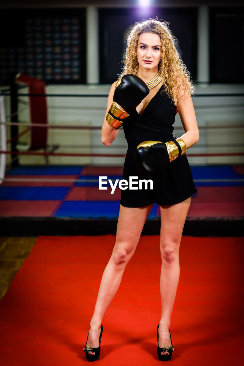 Portrait of beautiful young woman wearing gloves while standing on red carpet