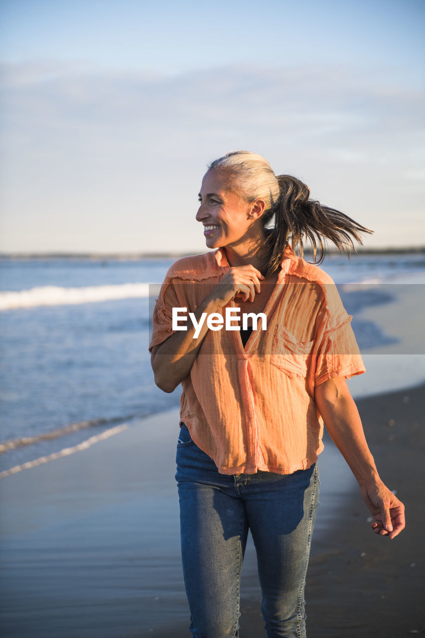 Gray haired woman enjoying the beach at sunset