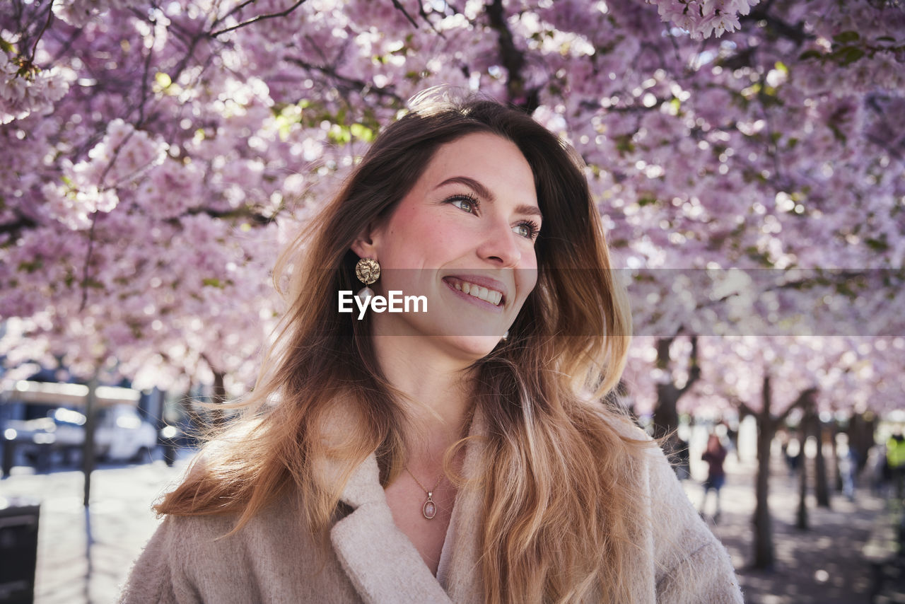 Young woman standing under cherry blossom