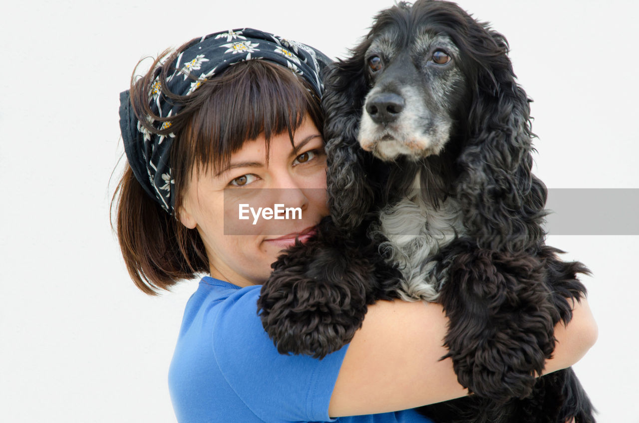 Portrait of woman hugging cocker spaniel against white background