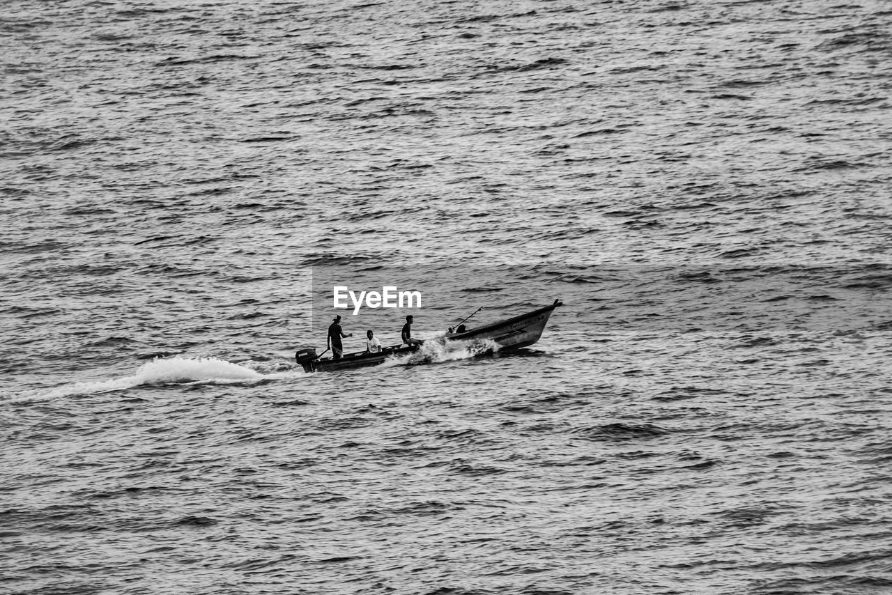 HIGH ANGLE VIEW OF MEN ON BOAT IN SEA