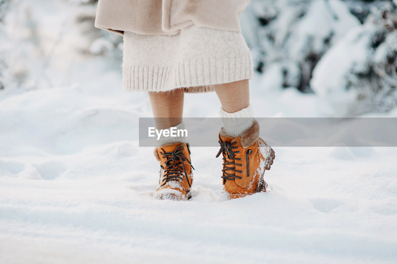 Warm winter boots in the snow. a girl in a beige faux fur coat walks through a snowy forest. fashion