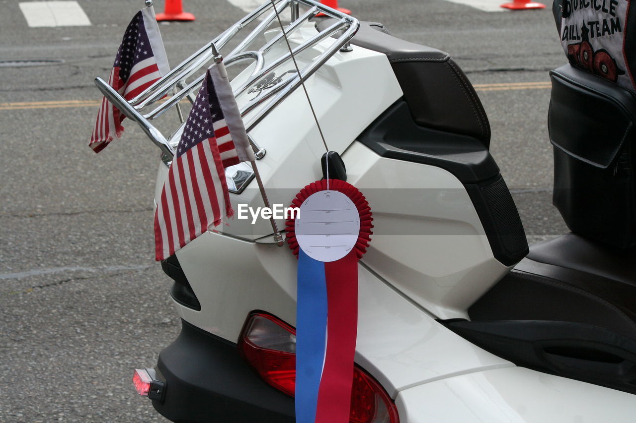 Midsection of person on motor scooter with american flag on fourth of july parade