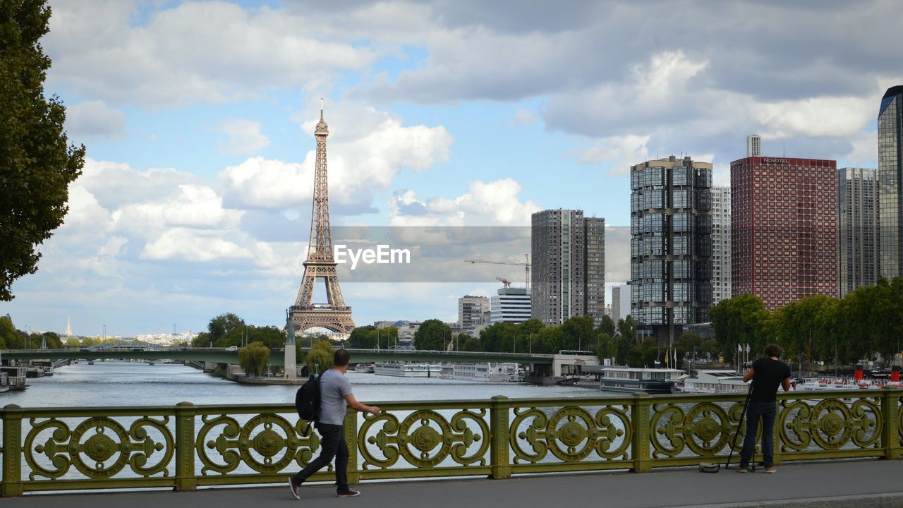 Men on bridge with eiffel tower and city in background