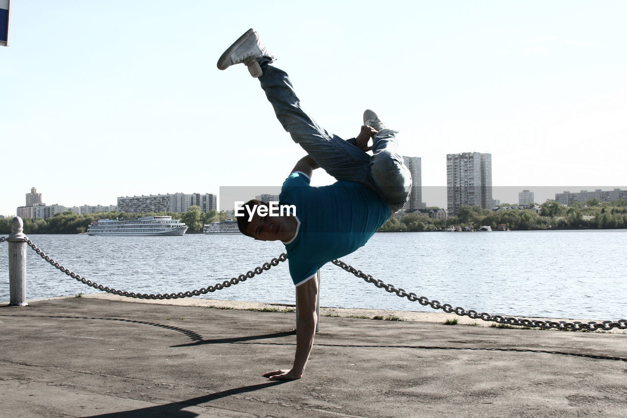 Man breakdancing against lake